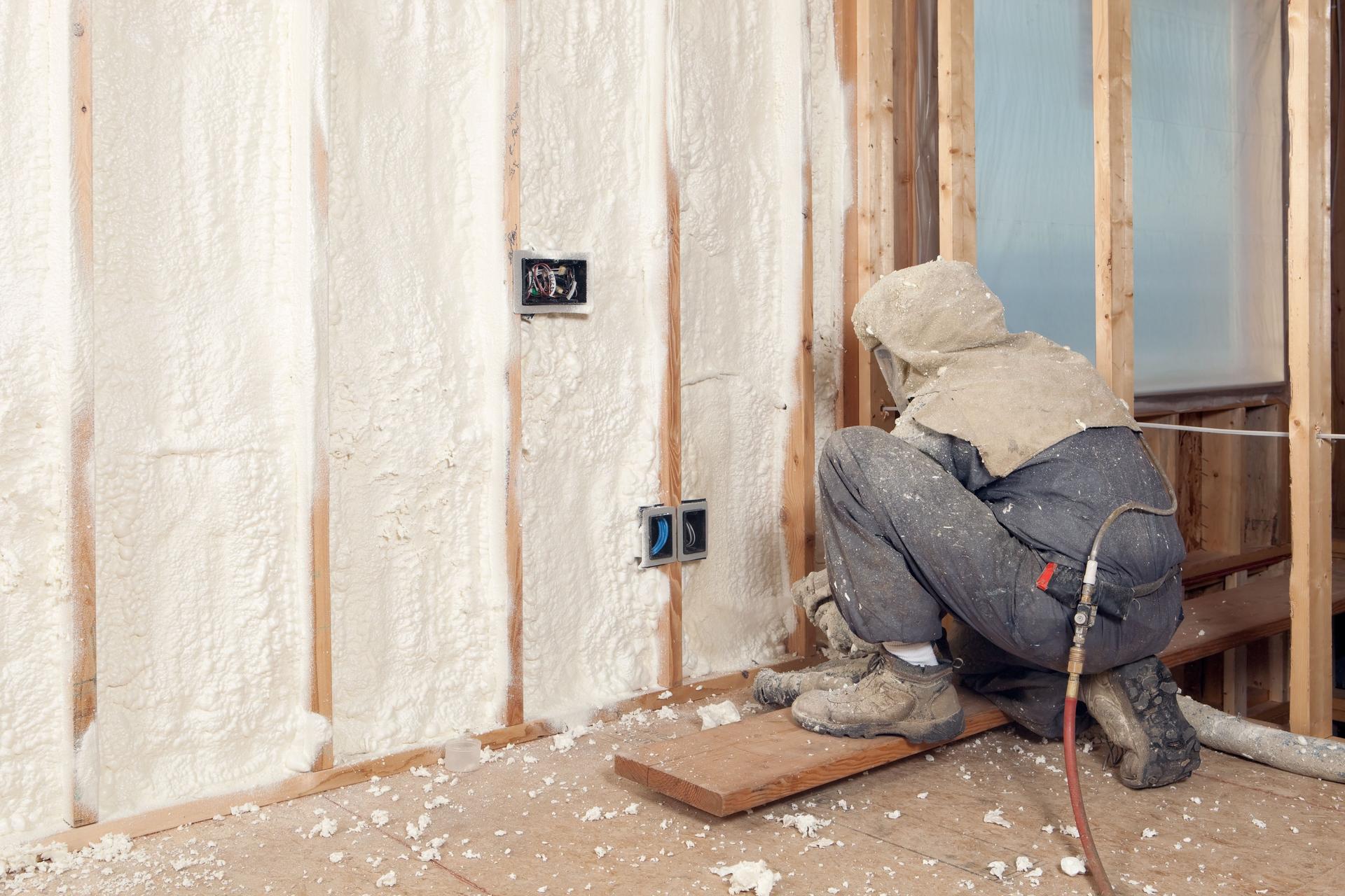 Worker Spraying Expandable Foam Insulation between Wall Studs